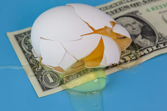 A broken egg on top of a dollar bill